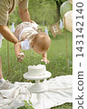 The child first birthday. The father holds the child above the cake. The cake is broken outdoors. 143142140