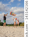 A father and his children are flying a kite in the sky on the beach 143142166