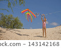 The child is hanging a swimsuit on a clothesline next to a kite. 143142168