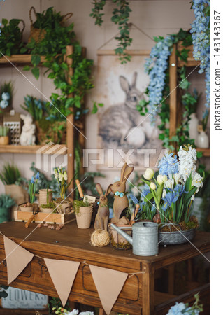Spring still life with Easter bunnies, flowers, and gardening tools Spring still life with Easter bunnies, flowers, and gardening tools 143143367