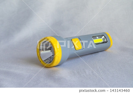 Flashlight placed on a light grey surface during daytime inside a room Flashlight placed on a light grey surface during daytime inside a room 143143460