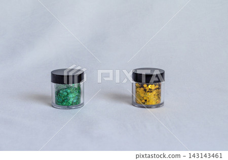 Green and yellow glitter in small containers on white surface Green and yellow glitter in small containers on white surface 143143461
