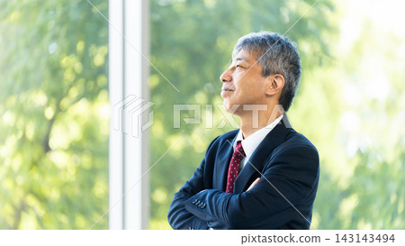 一位雙臂交叉的資深男性商人 一位雙臂交叉的資深男性商人 143143494