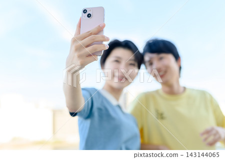 微笑的男女正在用智慧型手機自拍。 微笑的男女正在用智慧型手機自拍。 143144065