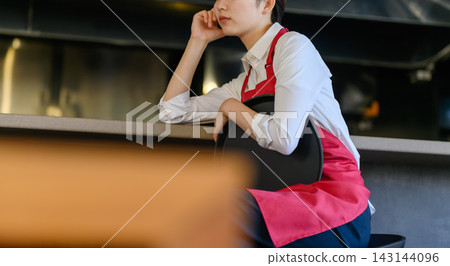 餐廳裡一位正在休息的女服務生。 143144096