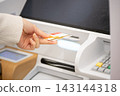 A woman's hands as she inserts her cash card into a bank ATM. 143144318