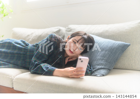 A woman watching a smartphone on a sofa 143144854
