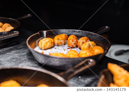 Black cast iron skillet with golden croquettes at a Maldives resort Black cast iron skillet with golden croquettes at a Maldives resort 143145179