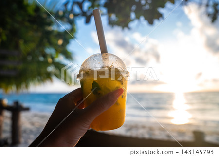 Hand holding a tropical fruit drink on a sunny beach in Maldives Hand holding a tropical fruit drink on a sunny beach in Maldives 143145793
