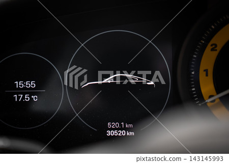 Close up of Porsche 911 Carrera digital cluster in daytime. Center car graphic, time 15 55, temp 17.5 C, trip 520.1 km, odometer 30520 km, yellow tach edge visible. Close up of Porsche 911 Carrera digital cluster in daytime. Center car graphic, time 15 55, temp 17.5 C, trip 520.1 km, odometer 30520 km, yellow tach edge visible. 143145993