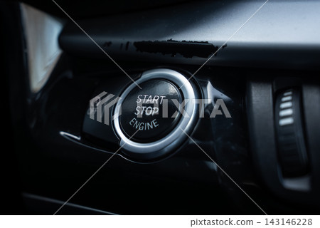 Close up interior view shows BMW X5 start stop engine button with metallic ring, adjacent OFF control, and knurled dial, in low moody light and shallow depth. Close up interior view shows BMW X5 start stop engine button with metallic ring, adjacent OFF control, and knurled dial, in low moody light and shallow depth. 143146228