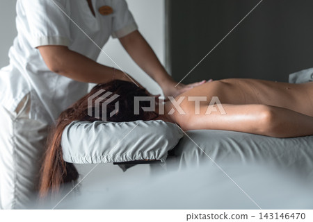 A spa therapist in a white uniform gives a back massage in a luxury Maldives resort room, soft diffused lighting and muted gray tones enhance an intimate, exclusive mood. A spa therapist in a white uniform gives a back massage in a luxury Maldives resort room, soft diffused lighting and muted gray tones enhance an intimate, exclusive mood. 143146470