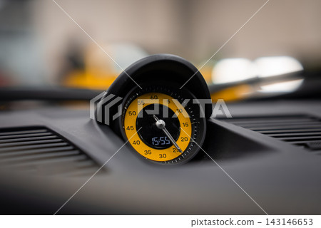 Close up shows yellow Sport Chrono stopwatch on Porsche 911 Carrera dashboard, hooded bezel and 60 minute markings, 15 55 readout, garage setting, shallow depth of field. Close up shows yellow Sport Chrono stopwatch on Porsche 911 Carrera dashboard, hooded bezel and 60 minute markings, 15 55 readout, garage setting, shallow depth of field. 143146653