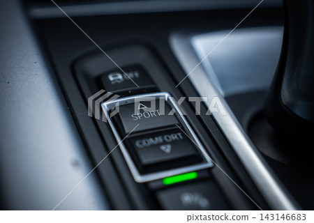 A BMW X5 center console shows the sport button between comfort and controls. A green indicator is on. Cool moody lighting and shallow depth of field focus on detail. A BMW X5 center console shows the sport button between comfort and controls. A green indicator is on. Cool moody lighting and shallow depth of field focus on detail. 143146683