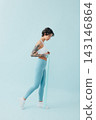 Full length of a young, slim woman practicing with a resistance band 143146864