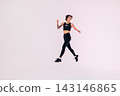 Full length of a young woman in black fitness wear jumping in a studio 143146865