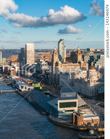 Aerial sunrise view of Liverpool waterfront with River Mersey, the Three Graces, Royal Liver Building, Cunard and Port of Liverpool buildings, Museum of Liverpool, few people strolling. Aerial sunrise view of Liverpool waterfront with River Mersey, the Three Graces, Royal Liver Building, Cunard and Port of Liverpool buildings, Museum of Liverpool, few people strolling. 143146974