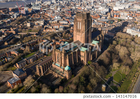 Aerial sunrise view of Liverpool centers on Liverpool Cathedral, with its tower and copper roofs over streets and parks. River Mersey, Pier Head, and museums appear. Aerial sunrise view of Liverpool centers on Liverpool Cathedral, with its tower and copper roofs over streets and parks. River Mersey, Pier Head, and museums appear. 143147016