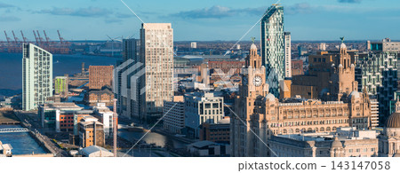 Aerial sunrise view of Liverpool, UK, with the Royal Liver Building, clock towers, River Mersey, modern high rises, angular glass, docklands, cranes, and distant ferries. Aerial sunrise view of Liverpool, UK, with the Royal Liver Building, clock towers, River Mersey, modern high rises, angular glass, docklands, cranes, and distant ferries. 143147058
