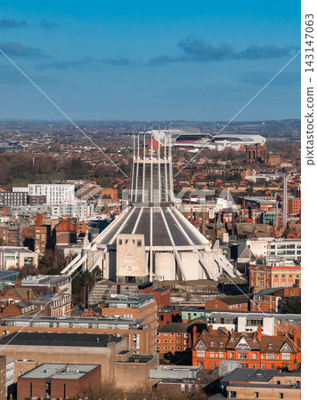 A high angle view shows Liverpool Metropolitan Cathedral and Anfield Stadium in central Liverpool, UK. Sunrise light defines concrete ribs and late winter clarity. A high angle view shows Liverpool Metropolitan Cathedral and Anfield Stadium in central Liverpool, UK. Sunrise light defines concrete ribs and late winter clarity. 143147063