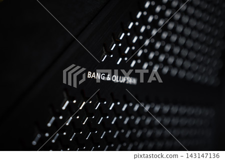 Tight close up shows a Bang and Olufsen speaker grille in a Yellow Lamborghini Urus, matte black hexagonal perforations, logo in focus, shallow depth, low key diagonal view. Tight close up shows a Bang and Olufsen speaker grille in a Yellow Lamborghini Urus, matte black hexagonal perforations, logo in focus, shallow depth, low key diagonal view. 143147136