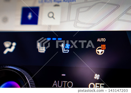 Close up dashboard view shows climate controls, heated seats, ventilated seats, AUTO heated wheel icon, rotary temperature knob, and map, in a modern showroom setting. Close up dashboard view shows climate controls, heated seats, ventilated seats, AUTO heated wheel icon, rotary temperature knob, and map, in a modern showroom setting. 143147203