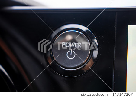 Illuminated POWER start stop button on a Lexus RX 450h plus dashboard, glossy black trim and metallic ring in focus, infotainment bezel at right, soft light, shallow depth of field. Illuminated POWER start stop button on a Lexus RX 450h plus dashboard, glossy black trim and metallic ring in focus, infotainment bezel at right, soft light, shallow depth of field. 143147207