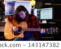 Woman playing on acoustic guitar in a recording studio 143147382