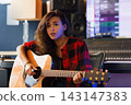 Young woman singing emotionally and playing one acoustic guitar  143147383