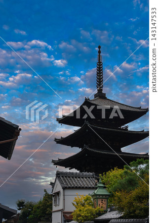 Yasaka Pagoda at Hokan ji Temple stands above rooftops in Higashiyama, Kyoto, at dusk. Stacked eaves, a tall finial, greenery, and a copper lantern add detail. Yasaka Pagoda at Hokan ji Temple stands above rooftops in Higashiyama, Kyoto, at dusk. Stacked eaves, a tall finial, greenery, and a copper lantern add detail. 143147533