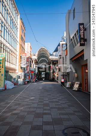 A quiet shopping street in central Hiroshima leads to a vaulted arcade, with Japanese signs, cafe and restaurant boards, and orderly storefronts on a calm morning. A quiet shopping street in central Hiroshima leads to a vaulted arcade, with Japanese signs, cafe and restaurant boards, and orderly storefronts on a calm morning. 143147945