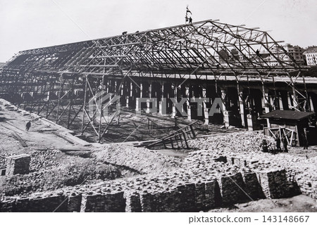 Workers stand on trusses of a pavilion under construction in Riga, Latvia. Black and white, wide composition, deep shadows, early 20th century industrial build. Workers stand on trusses of a pavilion under construction in Riga, Latvia. Black and white, wide composition, deep shadows, early 20th century industrial build. 143148667