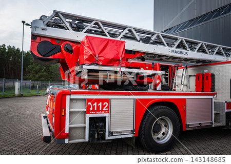Close view shows Magirus fire truck in Latvia with 32 m ladder, 112 number, and vugd.gov.lv on side, parked by a modern industrial building in daytime. Close view shows Magirus fire truck in Latvia with 32 m ladder, 112 number, and vugd.gov.lv on side, parked by a modern industrial building in daytime. 143148685
