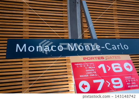 Monaco Monte Carlo signage sits above a directional panel for gates, VIP lounges, media, and accessible areas in a modern hall with wood slats and metal supports. Monaco Monte Carlo signage sits above a directional panel for gates, VIP lounges, media, and accessible areas in a modern hall with wood slats and metal supports. 143148742