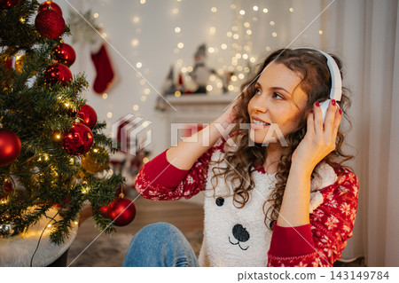 Young woman enjoying Christmas music with headphones at home 143149784
