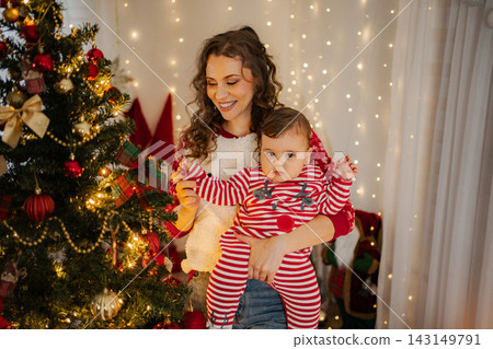 Mother holding baby celebrating Christmas at home Mother holding baby celebrating Christmas at home 143149791