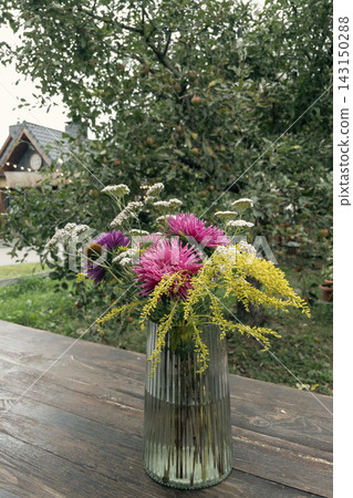 Colorful autumn wildflower bouquet in a ribbed glass vase outdoors Colorful autumn wildflower bouquet in a ribbed glass vase outdoors 143150288