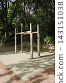 Wooden outdoor fitness bars installed in a public park surrounded by trees. Exercise equipment for strength training, calisthenics and healthy active lifestyle in a green recreation area. 143151038