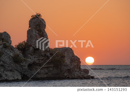 壯麗的岩石海岸線和地平線在溫暖的夕陽餘暉中若隱若現。 壯麗的岩石海岸線和地平線在溫暖的夕陽餘暉中若隱若現。 143151293
