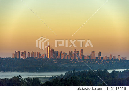 Golden hour city skyline with a construction crane and fog Golden hour city skyline with a construction crane and fog 143152626