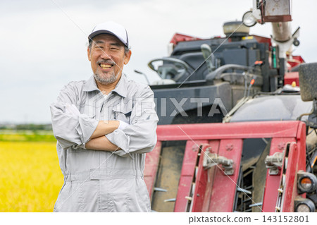 Senior man standing in front of a combine harvester Senior man standing in front of a combine harvester 143152801