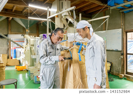 一位家長和孩子正在檢查米的品質。 一位家長和孩子正在檢查米的品質。 143152984