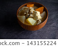 A close-up of a hearty pork and vegetable soup with tofu and vegetables. 143155224