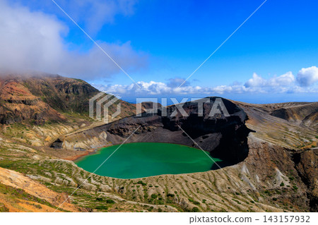 The beautiful Okama crater of Mount Zao, filled with emerald green water in September, against a blue sky. The beautiful Okama crater of Mount Zao, filled with emerald green water in September, against a blue sky. 143157932