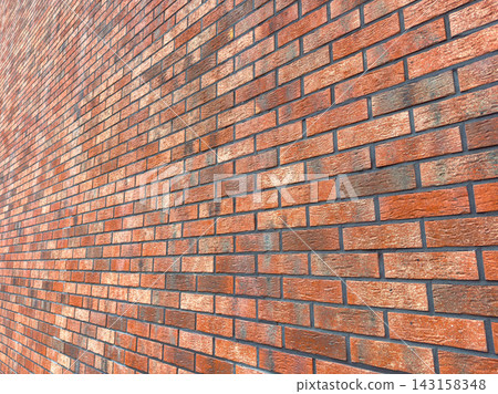Brick wall with rectangular bricks arranged in a pattern showing different shades of red and orange colors in a well-lit setting Brick wall with rectangular bricks arranged in a pattern showing different shades of red and orange colors in a well-lit setting 143158348