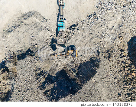Granite quarry operation showing machinery and raw stone materials in a work area during daylight Granite quarry operation showing machinery and raw stone materials in a work area during daylight 143158372