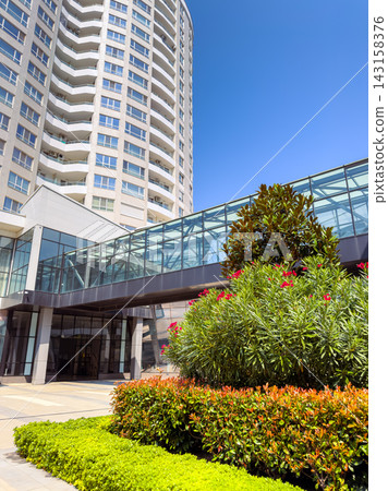Modern building with glass and greenery in a sunny setting Modern building with glass and greenery in a sunny setting 143158376