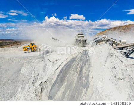 Granite quarry operation with heavy machinery and dust in a clear sky 143158399