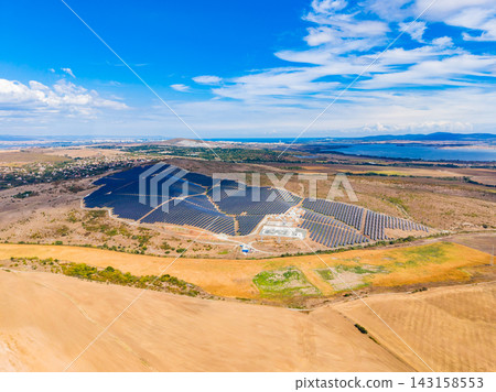 Solar panel installation in a wide open landscape near a body of water on a clear day with few clouds Solar panel installation in a wide open landscape near a body of water on a clear day with few clouds 143158553