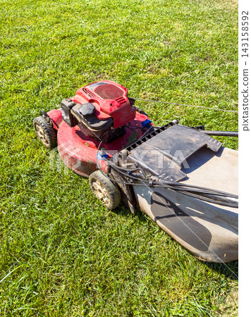 Lawn mower on grass during daytime while grass is being trimmed for maintenance Lawn mower on grass during daytime while grass is being trimmed for maintenance 143158592